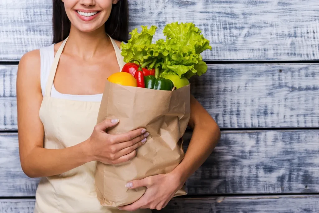 A woman holding a bag of vegetables in her hands.